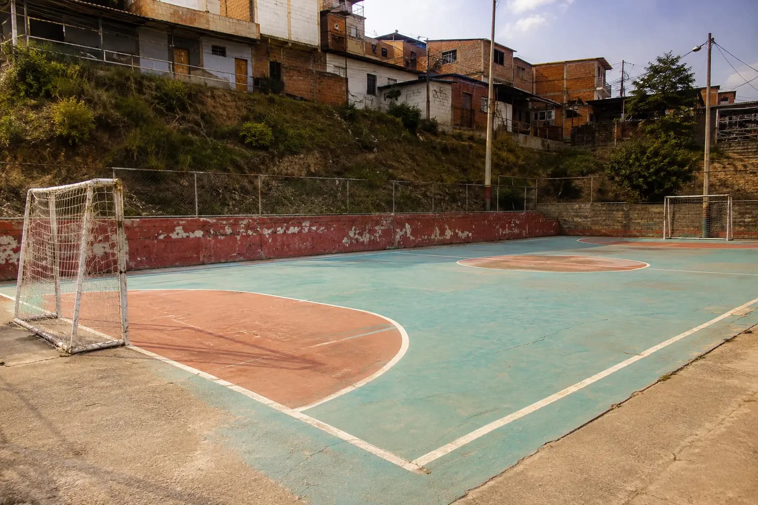 Cancha deportiva de cemento con la pintura del piso desgastada y agrietada